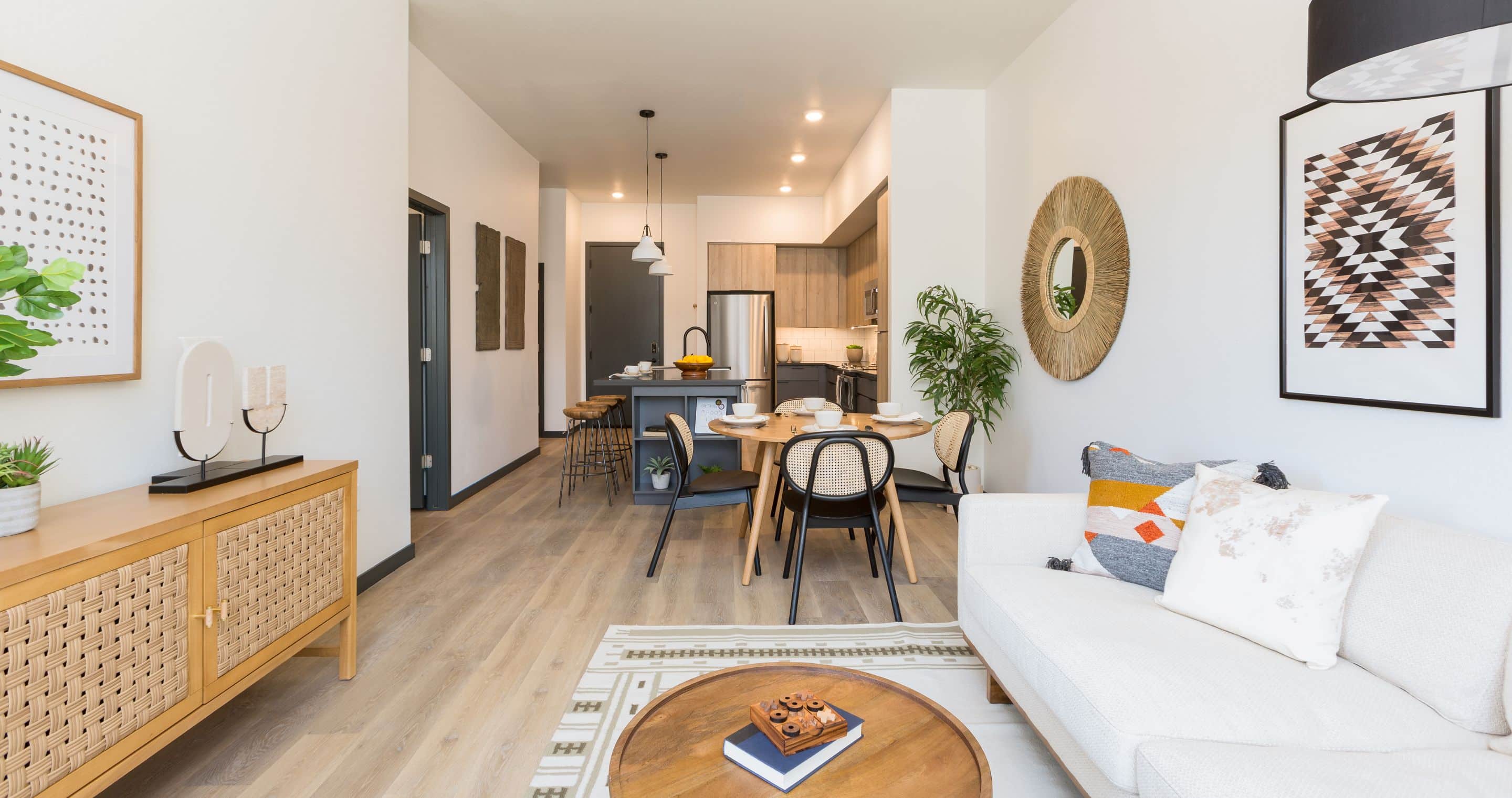 Modern open-concept living and dining area in Home - Lake Cameron, featuring light wood floors, neutral furniture, wall art, and a stylish kitchen in the background.