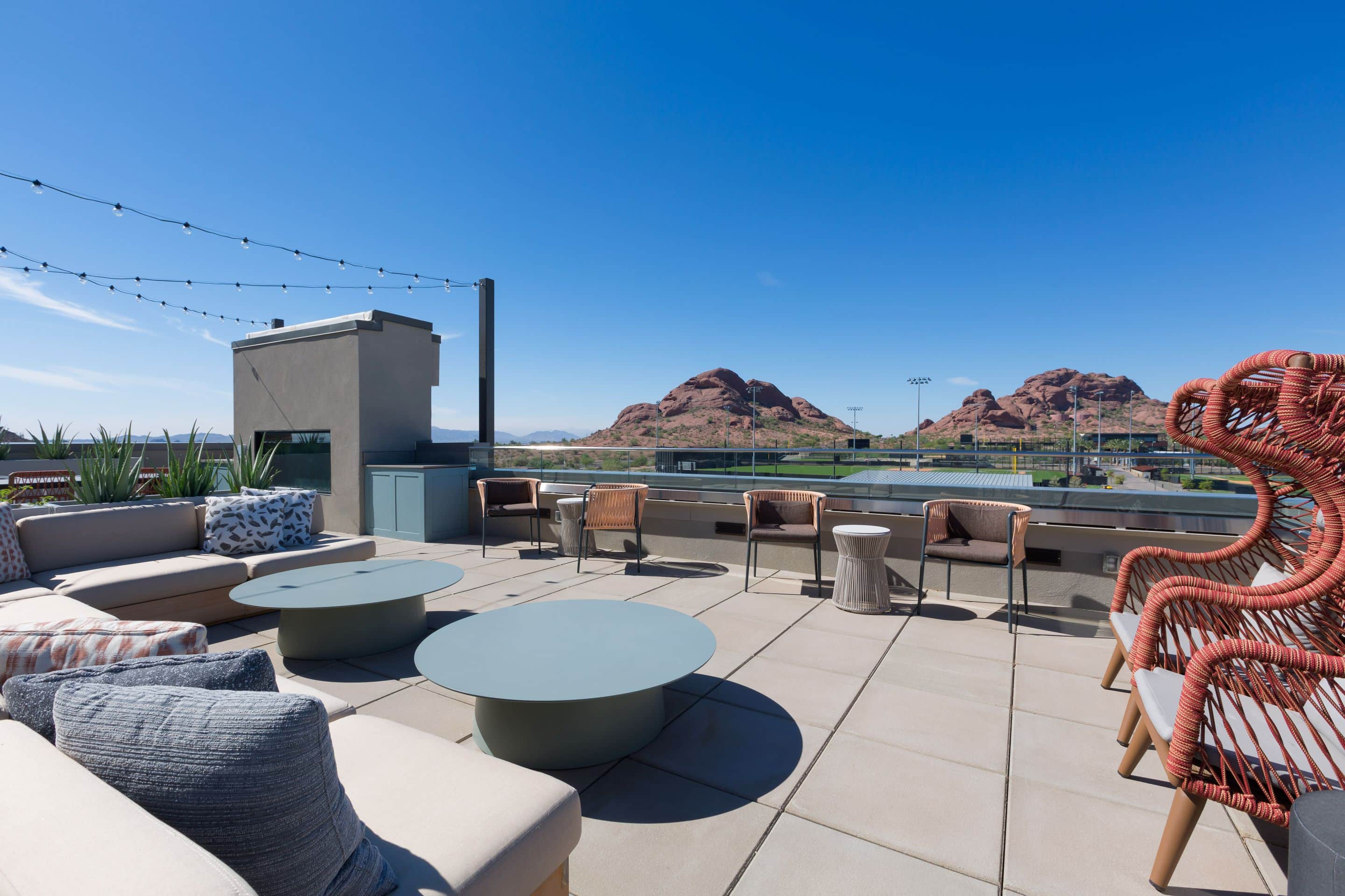 Modern rooftop patio with outdoor seating and tables at Home - Lake Cameron, strung with twinkling lights and offering a scenic mountain view under a clear blue sky.