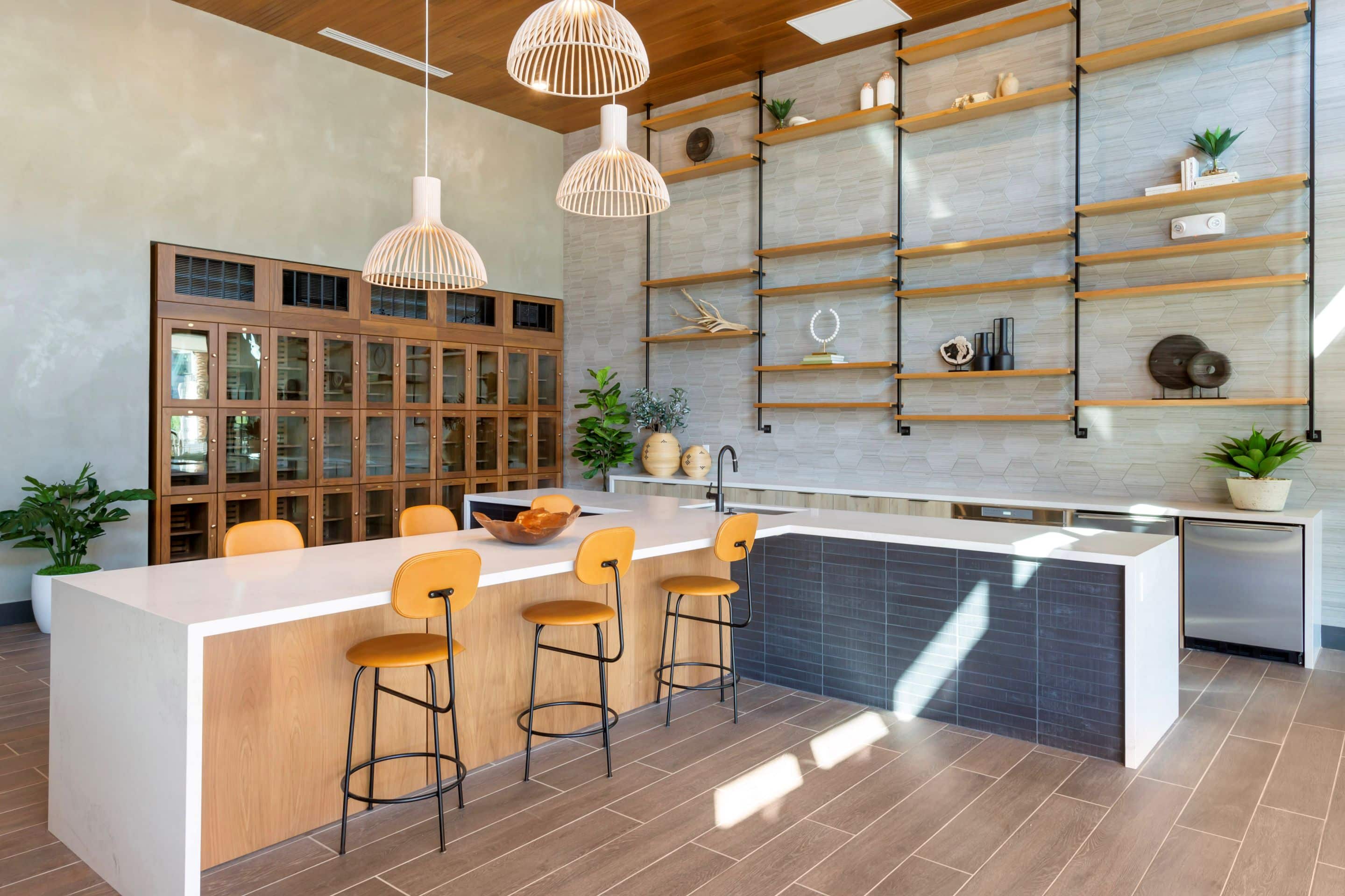 Modern kitchen in this Lake Cameron home features a large island, three wooden barstools, open shelves with décor, pendant lights, and floor-to-ceiling wine storage cabinets.